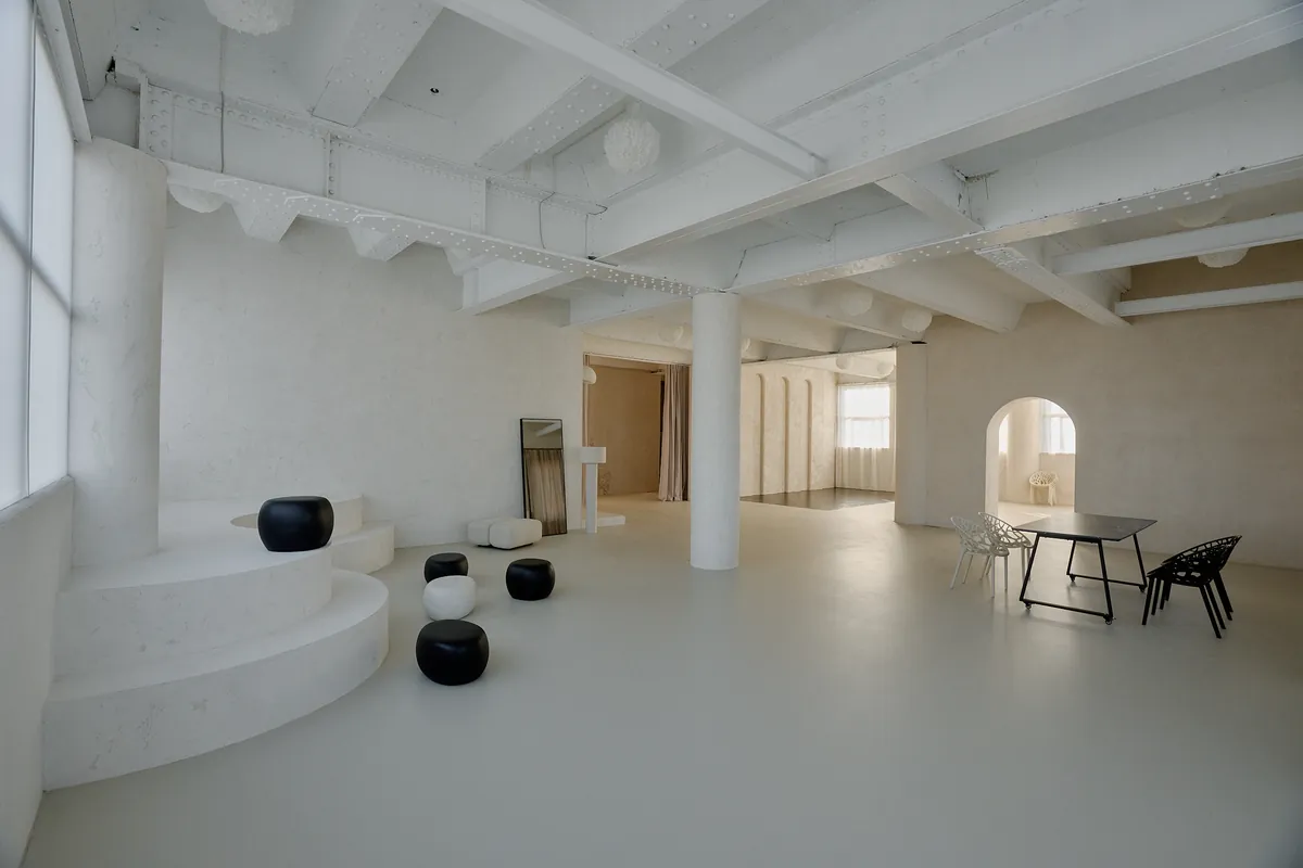 Gaia Studio — weiter Raumüberblick mit Poufs, Esstisch und Rundbogen